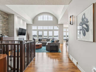 Experience luxury living in this stunning home featuring a grand, vaulted ceiling living area with a wall of windows overlooking the water.