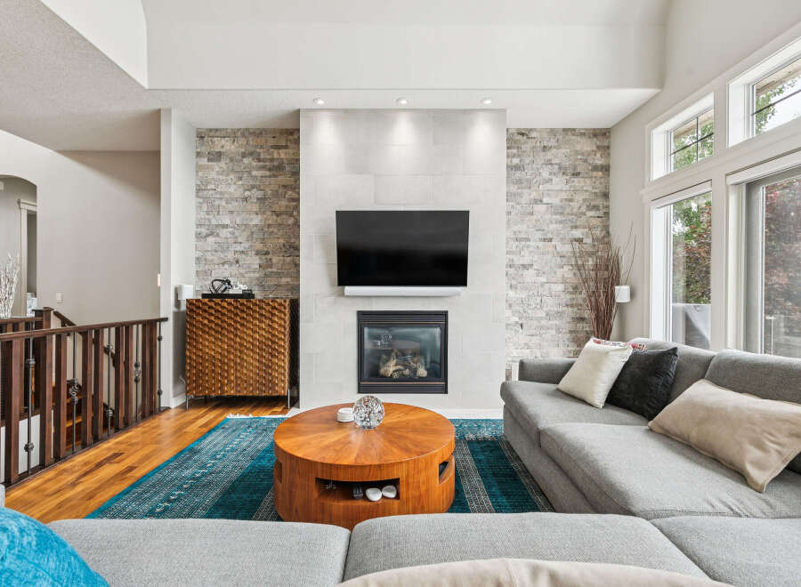 Experience modern living in this spacious great room, featuring a stunning floor-to-ceiling stone fireplace and a large flat-screen TV.