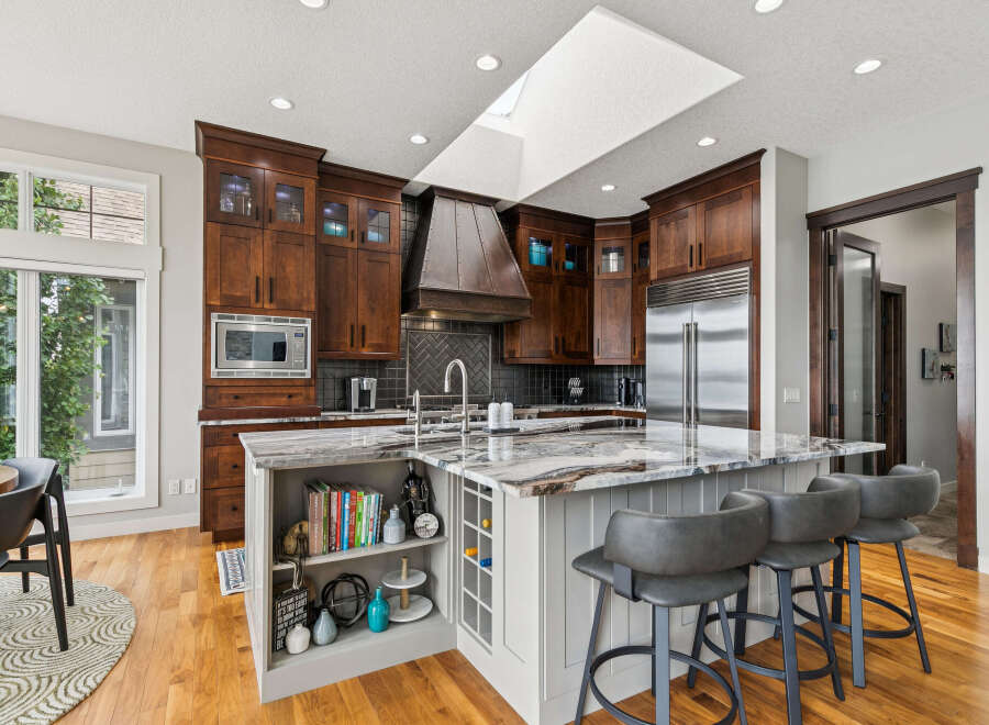 Experience luxury in this stunning kitchen featuring rich dark wood cabinetry, a dramatic copper range hood, and a spacious island with a unique marble countertop.