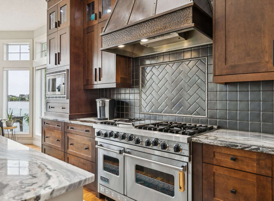 Experience luxury in this stunning kitchen featuring a professional-grade Viking range and a custom hammered metal range hood.