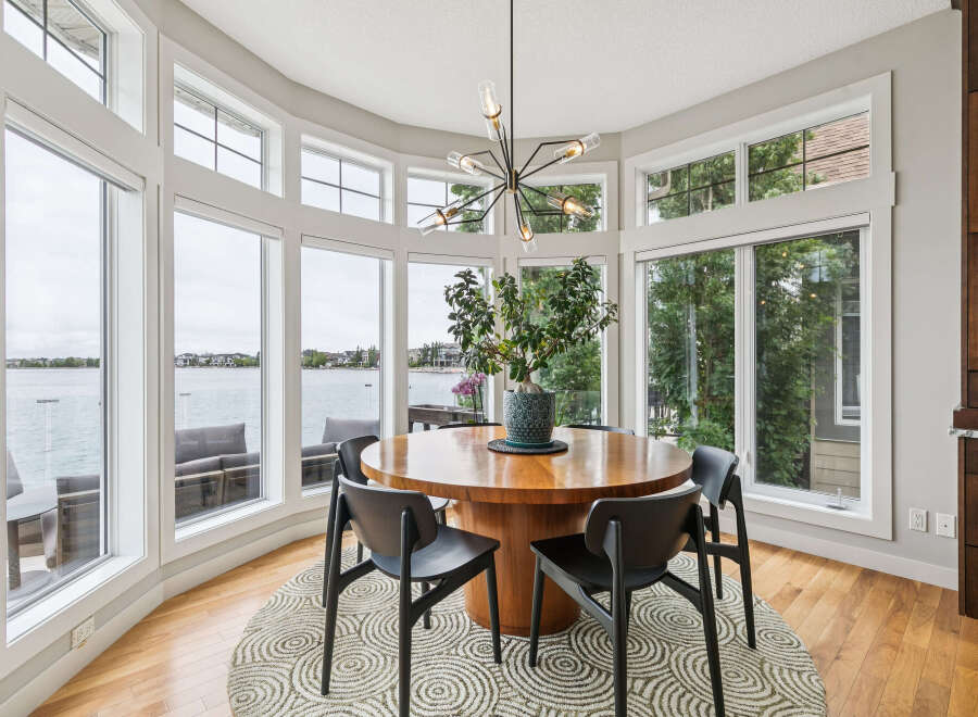 Enjoy breathtaking lake views from this stunning dining room, featuring a large circular table perfect for gatherings.