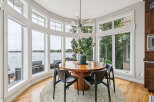Enjoy breathtaking lake views from this stunning dining room, featuring a large circular table perfect for gatherings.