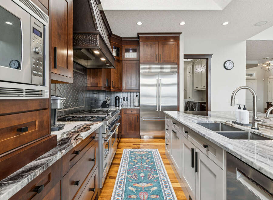 Experience culinary excellence in this stunning gourmet kitchen, featuring rich wood cabinetry, a professional-grade gas range, and a sleek stainless steel refrigerator.