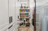 Discover ample storage in this well-organized pantry, featuring custom white cabinetry with sleek black hardware.