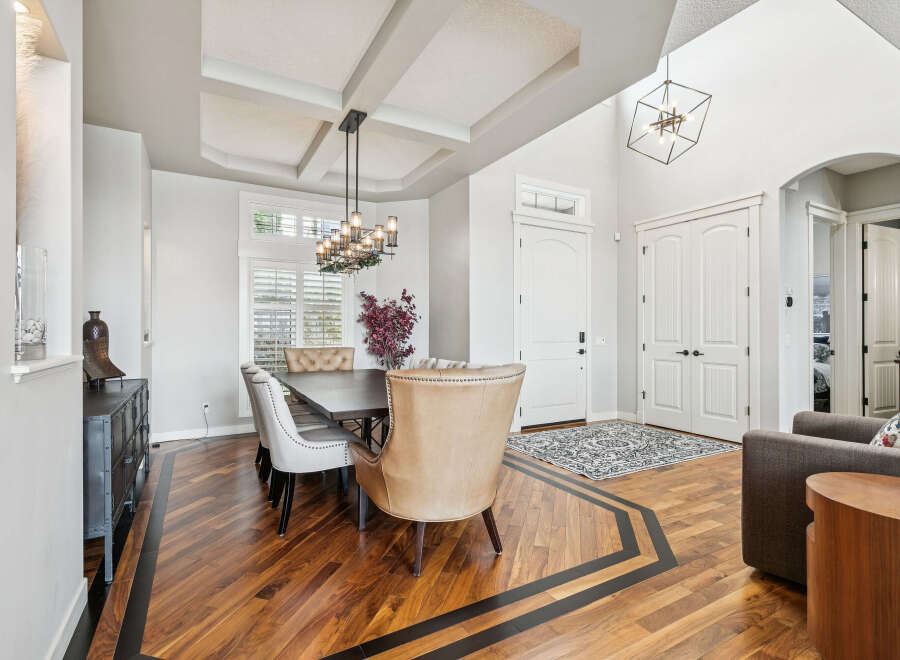 Experience elegant dining in this beautifully appointed space, featuring a stunning coffered ceiling and a modern chandelier.