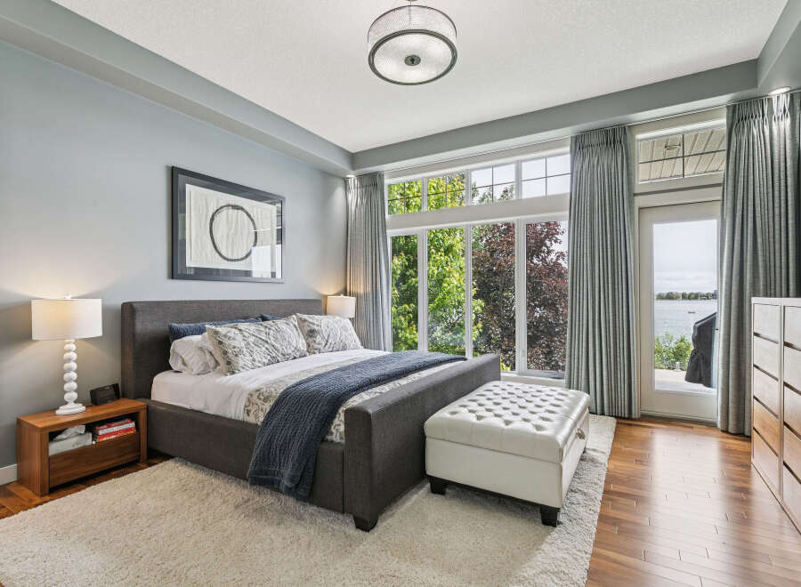 Experience luxurious living in this stunning master bedroom, featuring a king-size bed with plush bedding and a cozy throw.