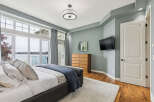 Experience luxurious waterfront living in this stunning master bedroom, featuring expansive windows that offer breathtaking lake views.
