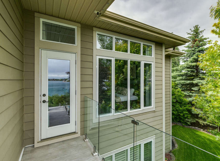 Experience breathtaking lake views from this stunning property, featuring a modern exterior with elegant siding and large windows.