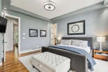Experience ultimate comfort in this serene master bedroom, featuring a plush king-sized bed adorned with elegant patterned pillows and a cozy blue quilt.