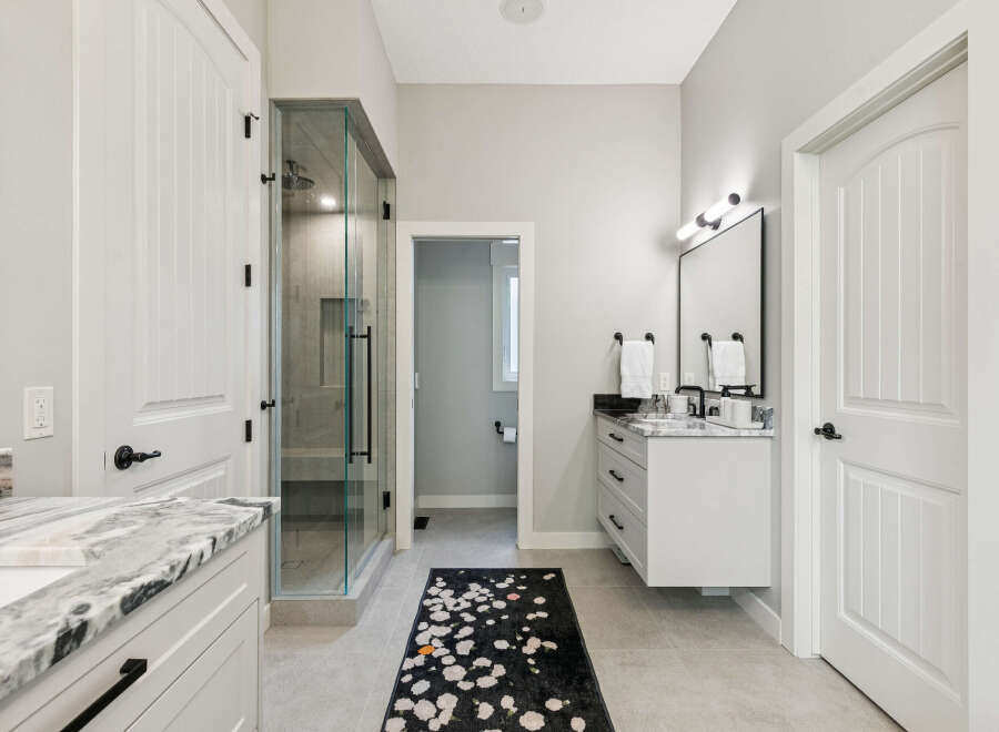 Experience luxury in this modern bathroom featuring a spacious glass-enclosed shower and a sleek floating vanity with a marble countertop.