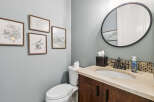 This powder room features a stylish vanity with a granite countertop and a dark wood cabinet, complemented by a mosaic tile backsplash.