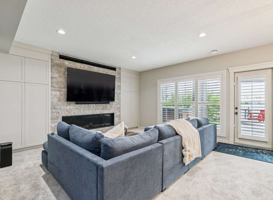 Experience modern living in this stylish living room, featuring a sleek fireplace with a mounted TV and ample built-in storage.