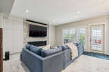 Experience modern living in this stylish living room, featuring a sleek fireplace with a mounted TV and ample built-in storage.
