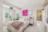 Experience luxury and comfort in this beautifully appointed bedroom, featuring a plush king-sized bed adorned with soft pink linens and a cozy faux fur throw.