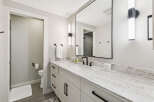 This modern bathroom features a sleek white vanity with a stunning marble countertop and black hardware.