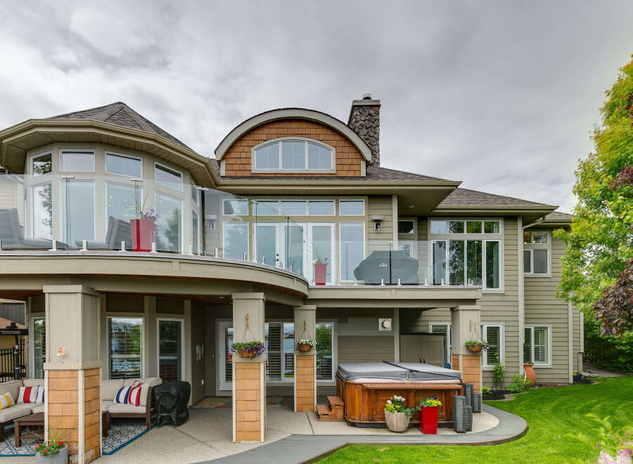 Experience luxury outdoor living with this stunning backyard featuring a spacious patio, a relaxing hot tub, and comfortable seating areas perfect for entertaining.