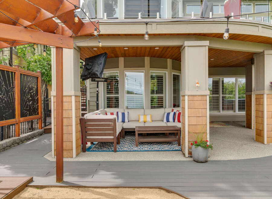 Enjoy outdoor living with this covered patio featuring a sectional sofa, coffee table, and string lights.