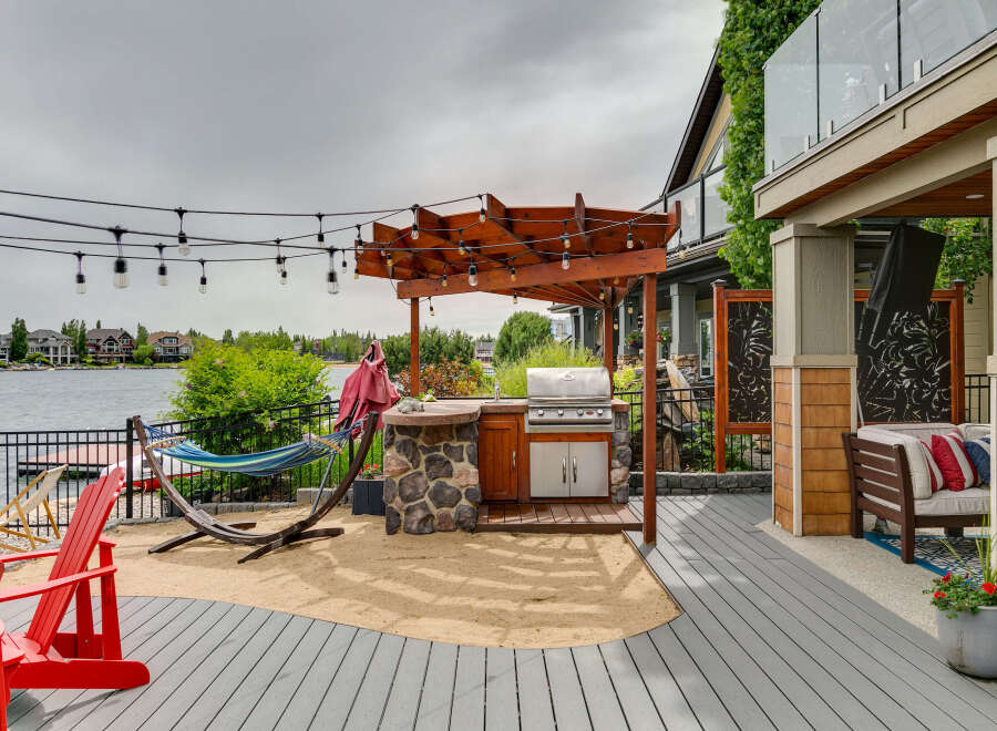 Enjoy outdoor living at its finest with this stunning backyard oasis, featuring a built-in outdoor kitchen under a wooden pergola, perfect for entertaining.