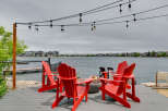 Enjoy breathtaking lake views from this stunning waterfront property, featuring a spacious deck with vibrant red Adirondack chairs perfect for relaxing.