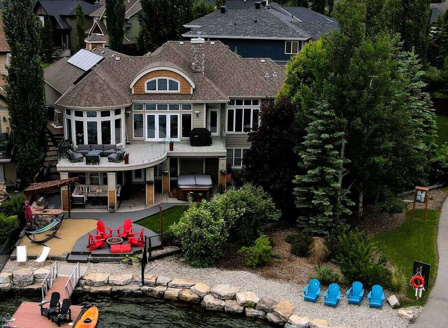 Experience luxury lakeside living in this stunning waterfront property, featuring a spacious deck with outdoor seating and a hot tub perfect for relaxation.