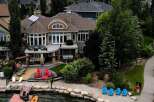 Experience luxury lakeside living in this stunning waterfront property, featuring a spacious deck with outdoor seating and a hot tub perfect for relaxation.