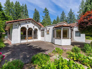 Charming stucco home with a red tile roof, featuring arched windows and a bay window for abundant natural light.