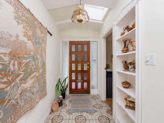 Step into this charming entryway featuring a beautiful wooden door with glass panes, flanked by frosted glass sidelights.
