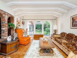 Step into this charming living room featuring a striking brick fireplace and an abundance of natural light pouring in through arched windows.