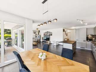 Experience modern living in this spacious open-plan home, featuring a sleek kitchen island and a cozy living area with a fireplace.