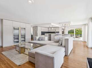 Experience modern luxury in this spacious open-concept living area, featuring a sleek sectional sofa and a stylish glass coffee table.