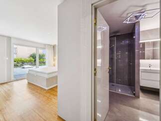 Step into a modern oasis with this stunning property, featuring a spacious bedroom with direct access to a private patio and lush greenery.
