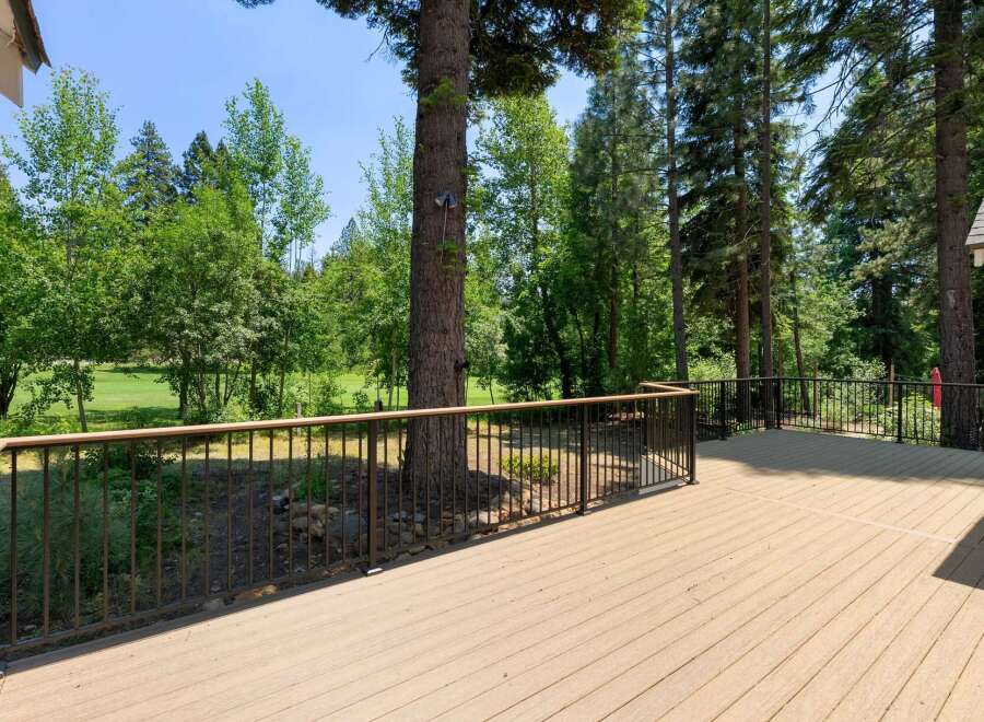 Enjoy the outdoors from this expansive deck, offering stunning views of lush greenery and a golf course.