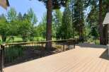 Enjoy the outdoors from this expansive deck, offering stunning views of lush greenery and a golf course.