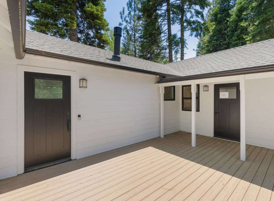 Experience modern living in this newly constructed home, featuring a sleek white exterior and a spacious wooden deck perfect for outdoor entertaining.