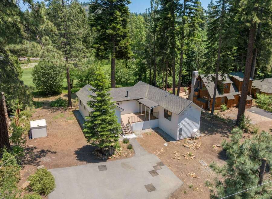 Nestled amidst tall pine trees, this charming white home offers a serene retreat.