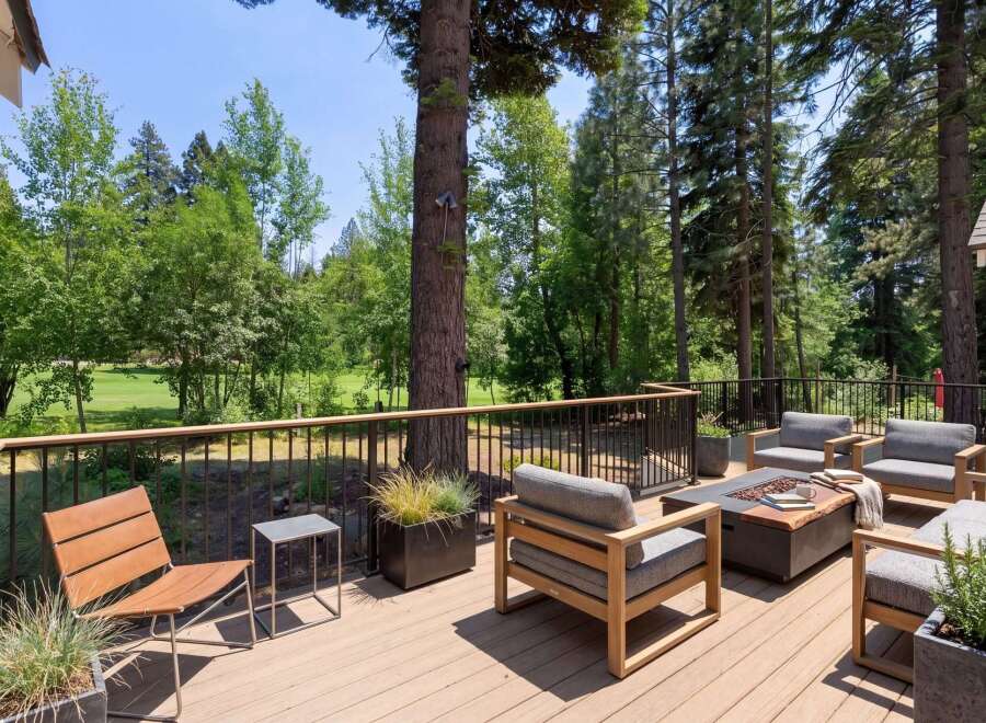 Experience outdoor living at its finest on this expansive deck, perfect for entertaining or relaxing amidst a serene, wooded setting with golf course views.