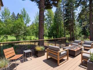 Experience outdoor living at its finest on this expansive deck, perfect for entertaining or relaxing amidst a serene, wooded setting with golf course views.