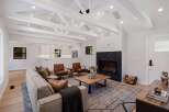 Experience modern living in this stunning living room, featuring a dramatic black marble fireplace and vaulted ceilings with exposed beams.