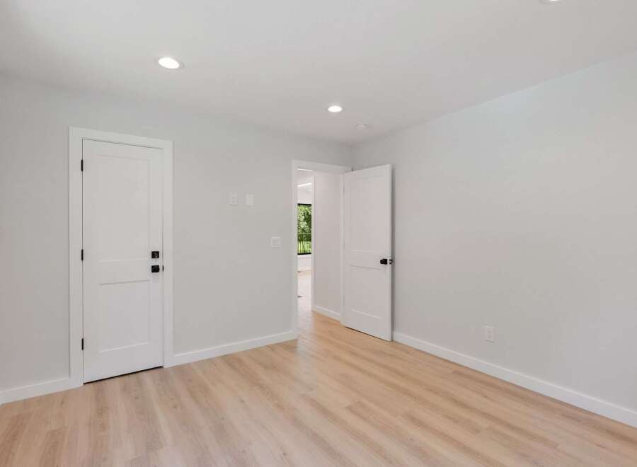 Step into this bright and airy room featuring a modern aesthetic with clean white walls and sleek doors.