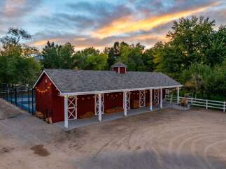 Experience rustic charm with this stunning red barn, perfect for equestrian enthusiasts or as a versatile event space.