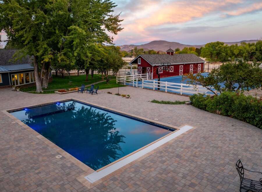Experience luxury outdoor living with this stunning property featuring a rectangular swimming pool and a full-size basketball court.