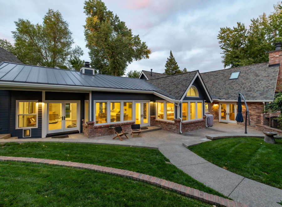 This stunning home features a modern dark blue exterior with contrasting brick accents and a sleek metal roof.