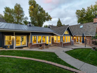 This stunning home features a modern dark blue exterior with contrasting brick accents and a sleek metal roof.