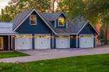 This stunning property features a spacious multi-car garage with classic white doors and dark hardware, set against a deep blue siding.