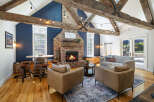 Experience rustic charm in this inviting living room, featuring exposed wooden beams and a striking brick fireplace.