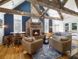 Experience rustic charm in this inviting living room, featuring exposed wooden beams and a striking brick fireplace.