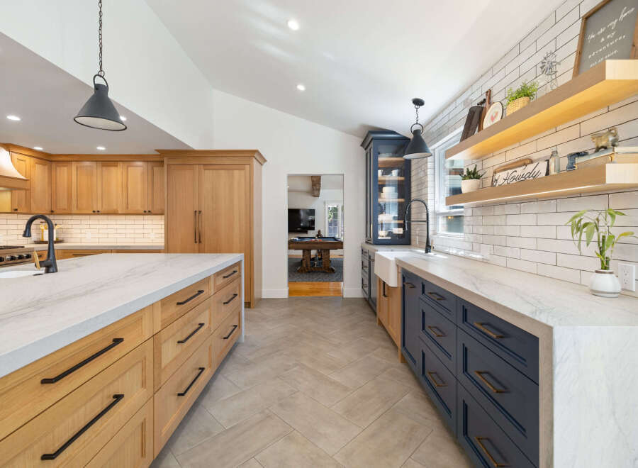 Experience the perfect blend of modern and rustic in this stunning kitchen, featuring custom wood cabinetry and sleek navy blue lower cabinets.