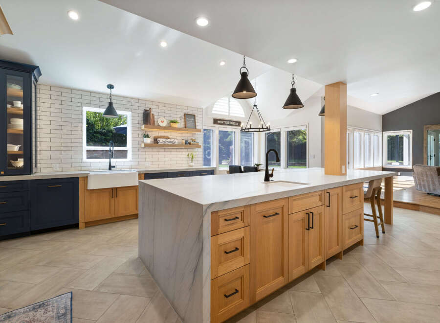 Experience the epitome of modern farmhouse living in this stunning kitchen, featuring a spacious island with a marble countertop and natural wood cabinetry.