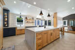 Experience the epitome of modern farmhouse living in this stunning kitchen, featuring a spacious island with a marble countertop and natural wood cabinetry.