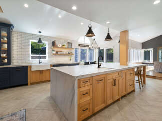 Experience the epitome of modern farmhouse living in this stunning kitchen, featuring a spacious island with a marble countertop and natural wood cabinetry.